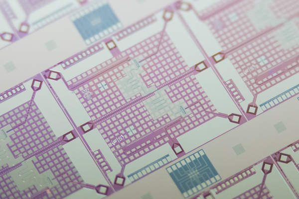 A superconducting qubit chip, a grid of pinks and blues, is shown