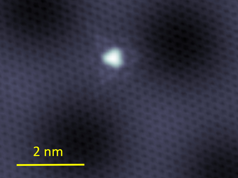 a bright white spot is in the center of a dark image, indicating the defect