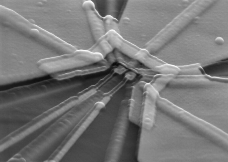 a greyscale scanning electron micrograph of a trapezoid-like semiconducting qubit with radial-like lines coming out of it