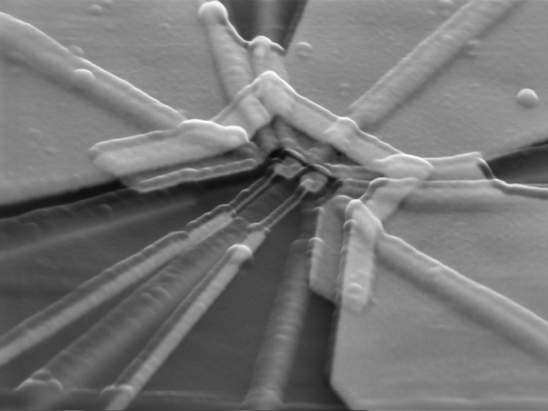 a greyscale scanning electron micrograph of a trapezoid-like semiconducting qubit with radial-like lines coming out of it